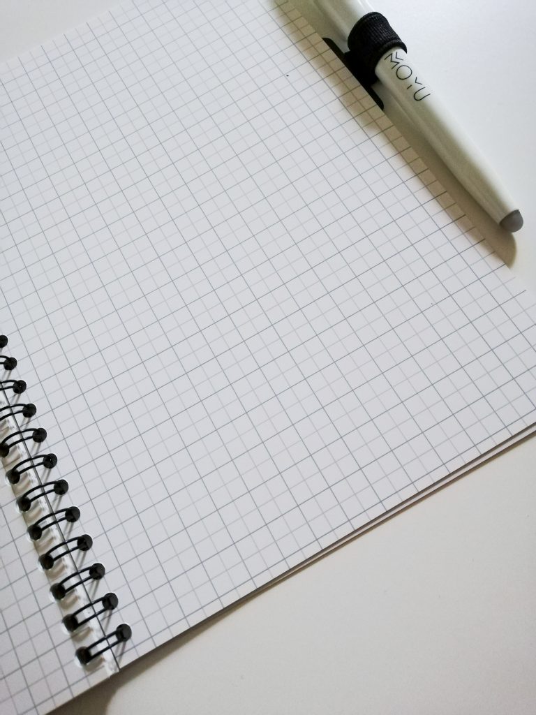 Opengeslagen MOYU duurzaam notitieboekje met ruitjespapier en een pen aan de zijkant